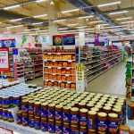 Corredor de supermercado com prateleiras abastecidas e diversos produtos organizados