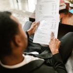 Profissional analisa documentos financeiros e planilhas em uma mesa de escritório.