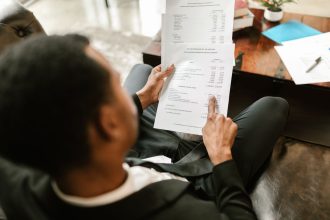 Profissional analisa documentos financeiros e planilhas em uma mesa de escritório.