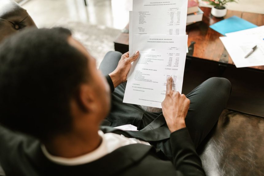 Profissional analisa documentos financeiros e planilhas em uma mesa de escritório.