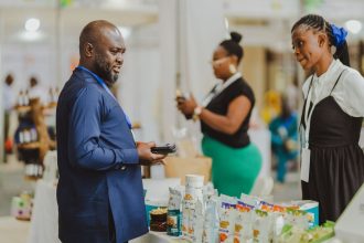 Profissionais conversam em um estande de feira comercial, diante de produtos expostos.