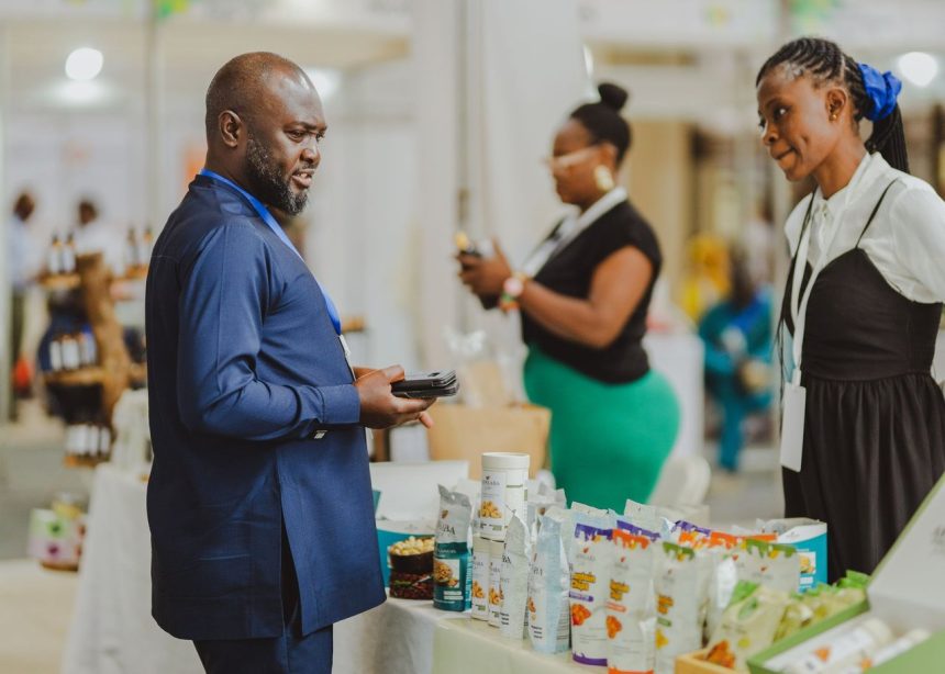 Profissionais conversam em um estande de feira comercial, diante de produtos expostos.